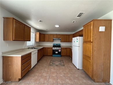 Kitchen featuring white appliances, a sink, under
