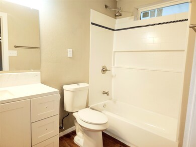 Bathroom with shower / bath combination, vanity, and a textured wall