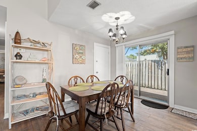 Dining room featuring light wood-type flooring, a chandelier, and a textured ceiling