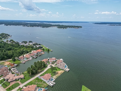 This aerial photo showcases a picturesque waterfront community with houses along a serene lake. The area features lush greenery and direct water access, ideal for boating and enjoying scenic views. Perfect for those seeking a tranquil lakeside lifestyle.