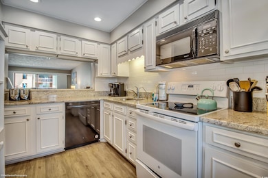 Kitchen featuring white cabinets, black appliances