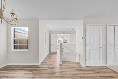 Hallway featuring a chandelier, light hardwood / w