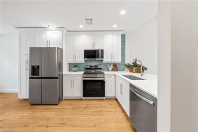 Kitchen featuring a sink, stainless steel appliances, backsplash, light countertops, and white cabinets