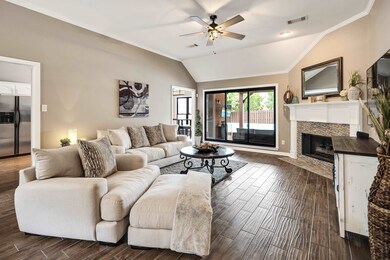 Living room with ceiling fan, dark wood-style flooring, ornamental molding, a fireplace, and lofted ceiling