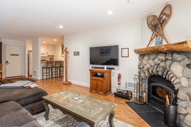 Living room with light wood-style flooring, recessed lighting, and a stone fireplace
