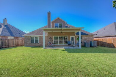 Rear view of property featuring a yard, a patio ar