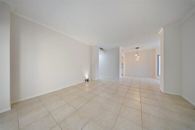 Spacious living area with neutral tile flooring, fresh paint, and seamless flow into the dining space.
