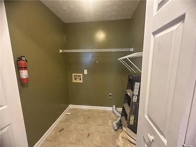 Washroom with hookup for an electric dryer, hookup for a washing machine, a textured ceiling, and light tile patterned floors