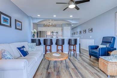 Living area with arched walkways, ceiling fan, recessed lighting, and light wood-style flooring
