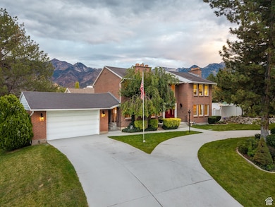 View of front facade with driveway, a mountain view, an attached garage, a front lawn, and brick siding