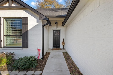 Doorway to property with brick siding and a shingled roof