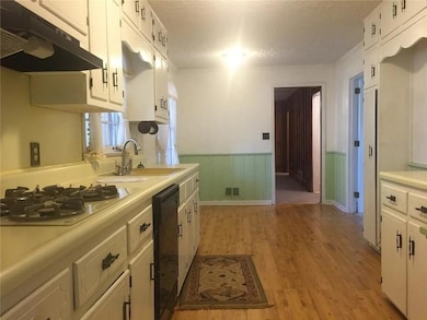 cabinet range hood, white cabinets, light countertops, and light wood-type flooring