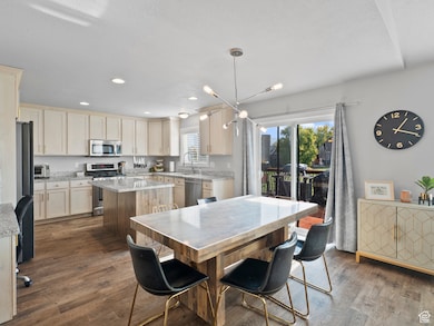 Dining room with dark wood-type flooring, a chandelier, and recessed lighting