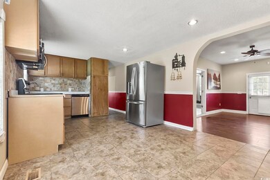Kitchen with appliances with stainless steel finishes, backsplash, light countertops, arched walkways, and ceiling fan
