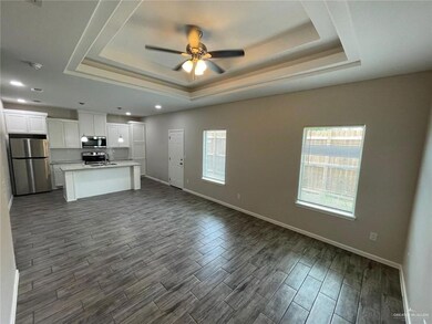 Unfurnished living room with a tray ceiling, dark wood-style floors, ceiling fan, and recessed lighting