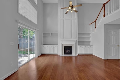 Unfurnished living room with a high ceiling, ceiling fan, a large fireplace, and wood finished floors