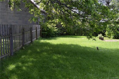 Rear of property enclosed by fence and thick hedge