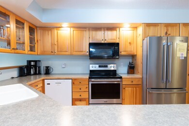 Kitchen with stainless steel appliances, glass insert cabinets, and light countertops