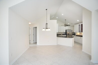 Kitchen with stainless steel fridge with ice dispenser, dark countertops, white cabinets, decorative backsplash, and recessed lighting