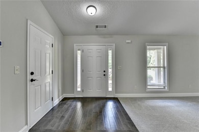 Entryway with a textured ceiling, baseboards, dark