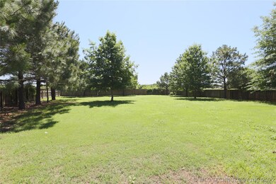 Large lot with trees and fields behind it.