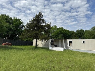 Back of property with covered porch, fence, and a lawn
