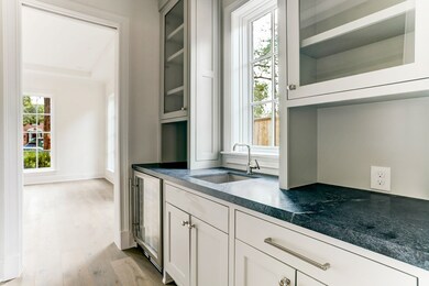 Butler's pantry is conveniently located near the dining room. The space is complete with a stunning Churchill Honed - Dark Grey soapstone with prep sink and built-in wine cooler, allowing for the perfect entertainment experience.