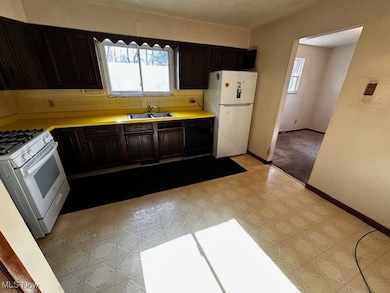 Kitchen featuring light countertops, dark brown cabinetry, light floors, backsplash, and white appliances