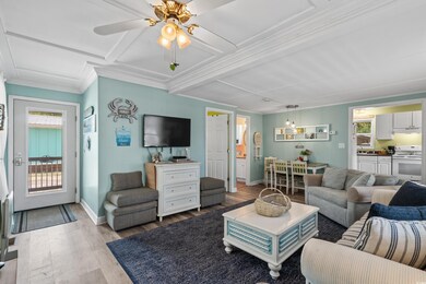 Living room featuring crown molding, light wood-style flooring, baseboards, coffered ceiling, and a ceiling fan