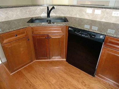 Kitchen featuring dishwasher, brown cabinetry, light wood-style floors, and decorative backsplash