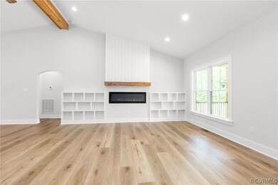 Unfurnished living room featuring light wood-type flooring, lofted ceiling with beams, and a fireplace