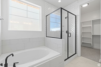 Full bathroom with a bath, a stall shower, marble finish floors, recessed lighting, and a spacious closet