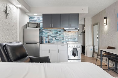 Kitchen with appliances with stainless steel finishes, a textured wall, a sink, a textured ceiling, and backsplash