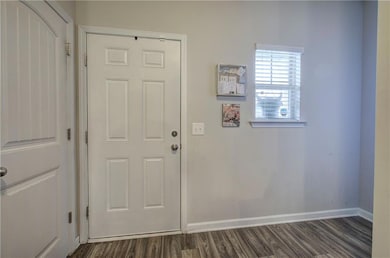 Doorway to outside with dark wood-style flooring and baseboards