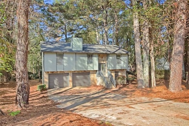 Bi-level home featuring driveway, a chimney, and an attached garage