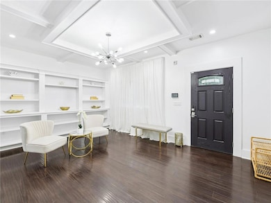 Living area with beamed ceiling, dark wood finished floors, a chandelier, and coffered ceiling