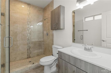 Full bath featuring a stall shower, toilet, and vanity