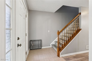 Entrance foyer featuring healthy amount of natural light, a textured ceiling, light tile patterned floors, and stairway