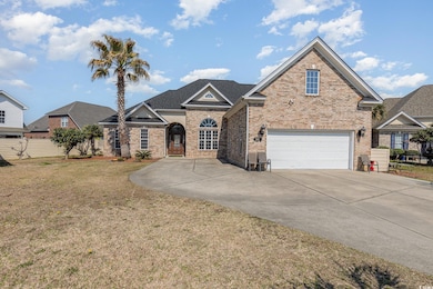 View of front facade featuring a front lawn, brick siding, driveway, and a garage