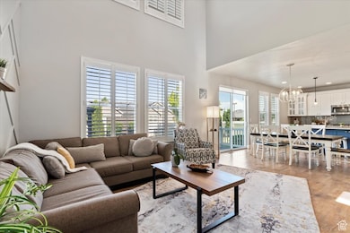 Living room with a chandelier, light wood finished floors, and a towering ceiling