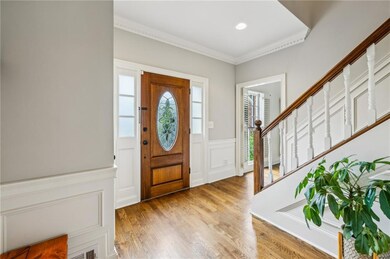 Foyer entrance with a decorative wall, a wainscoted wall, ornamental molding, light wood finished floors, and recessed lighting