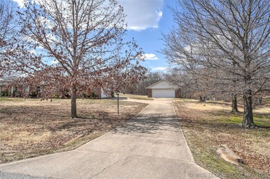Driveway is flanked by mature trees.