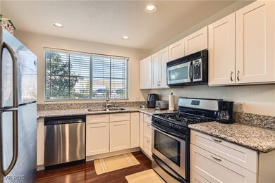 Kitchen with stainless steel appliances, dark wood finished floors, recessed lighting, white cabinets, and light stone counters