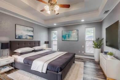 Bedroom with ceiling fan, a raised ceiling, dark w