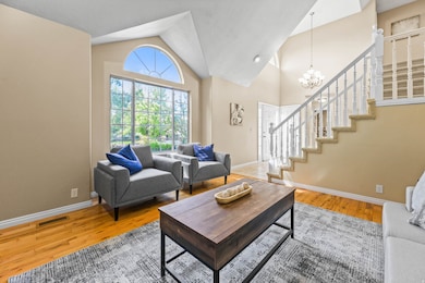 Living area featuring stairs, high vaulted ceiling, light wood-type flooring, and a chandelier