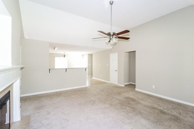 Unfurnished living room featuring lofted ceiling, a ceiling fan, light colored carpet, and a high end fireplace