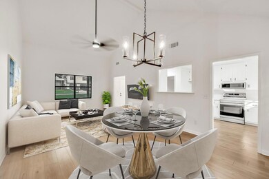 Dining space featuring high vaulted ceiling, a chandelier, light wood-style flooring, and baseboards