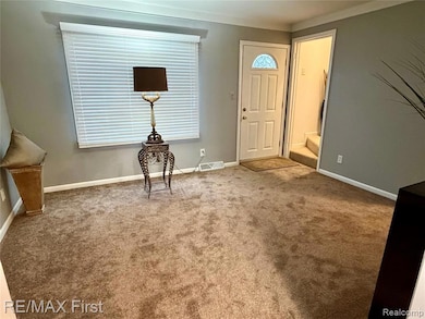 Carpeted foyer entrance with baseboards and stairway