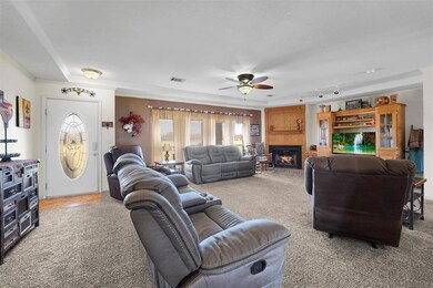 Carpeted living room with ceiling fan, a fireplace