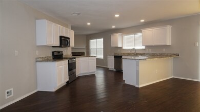 Kitchen featuring light stone countertops, white cabinetry, appliances with stainless steel finishes, and recessed lighting